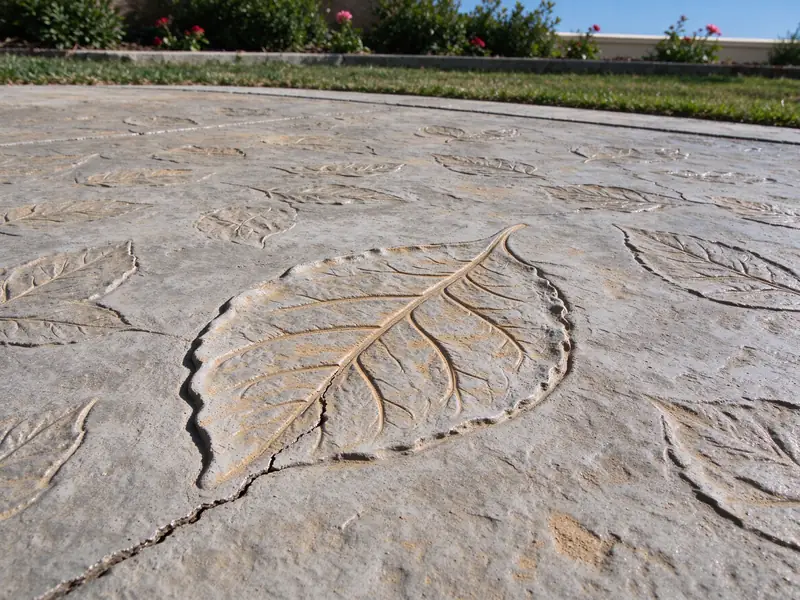 Crack running through a leaf-pattern stamped concrete surface